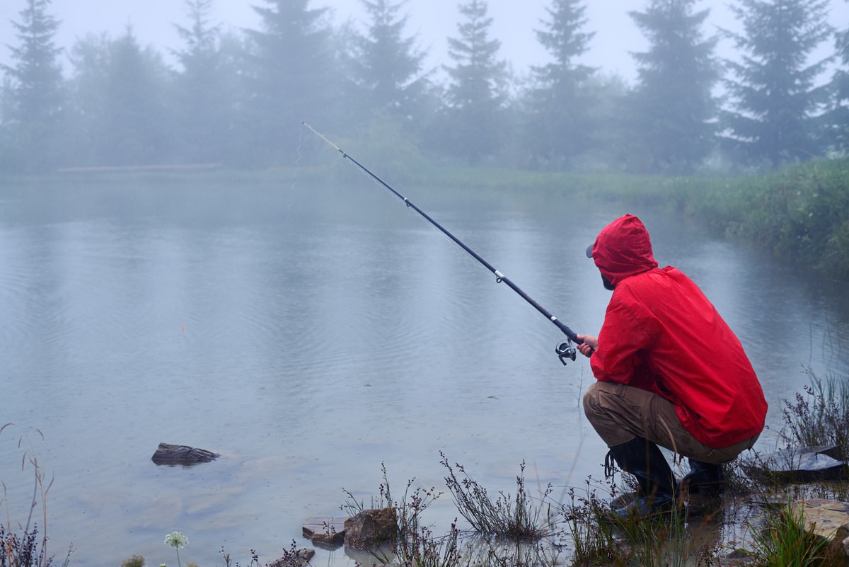 Homem com Casaco Vermelho Pescando na Chuva